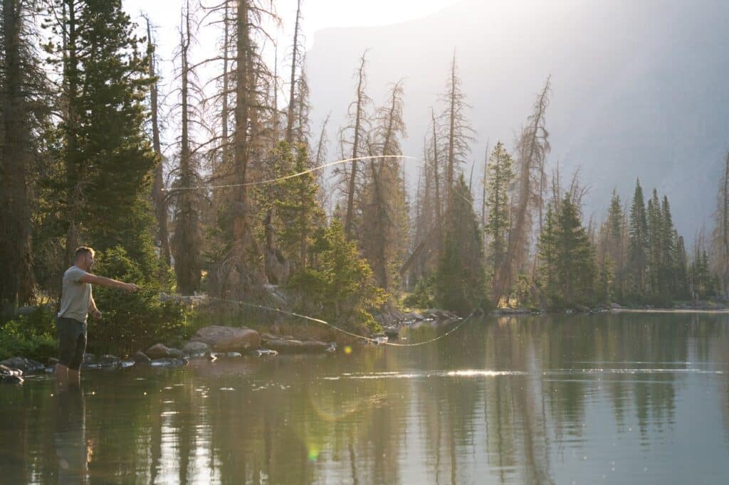 a man fly fishing in a mountain lake